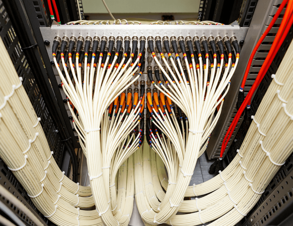 Close-up of bundled network data cables and patch panel in a server rack.